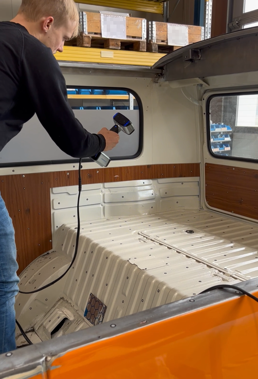 Foto von Mitarbeiter, scannt Ladeflaeche von VW T2 mit mobilen 3D Scanner