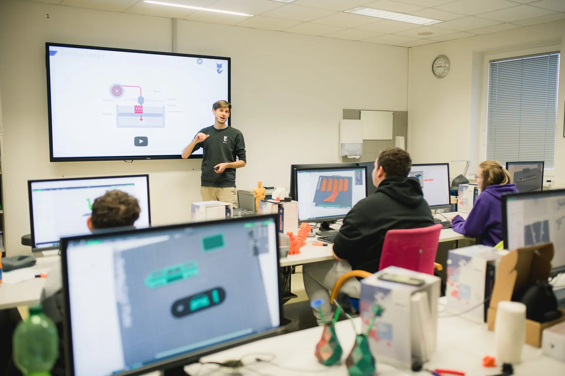 Foto von Mann der eine kleine Gruppe zum Thema 3D Druck unterrichtet